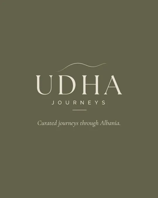 UDHA Journeys wordmark reversed on Olive with the line Curated journeys through Albania